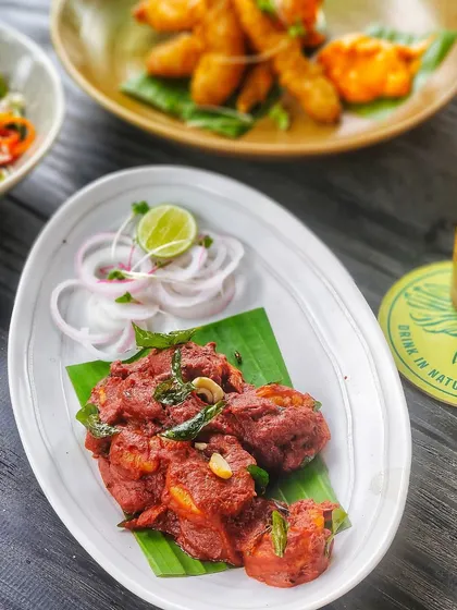 A plate of spicy chicken appetizer, perfectly paired with a cold beer and fresh onions.
