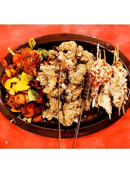 A platter showcasing a trio of our popular appetizers: a spicy chicken stir-fry, crispy crumbed chicken, and creamy malai chicken skewers.