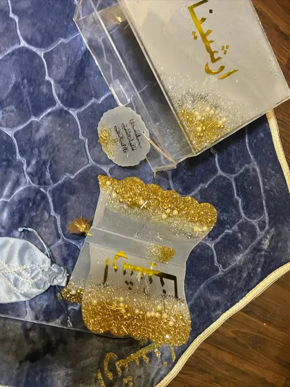Another view of the white and gold Eid gift set, showing the personalized name 'Arshina' on the Quran box and holder.
