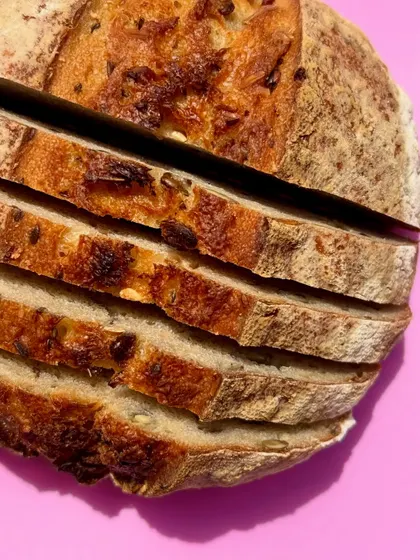 A close-up of our sliced seeded sourdough. You can see the open crumb and the distribution of pumpkin, melon, flax, and sesame seeds throughout the loaf.