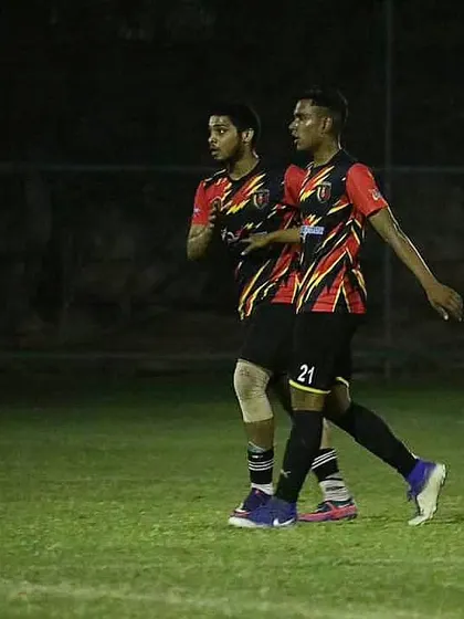 Two of our players in sync on the field during a night match, demonstrating teamwork and communication.