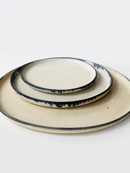 A stack of our dinner and side plates, showing how you can layer different sizes to create a complete and cohesive table setting. The dripping glaze effect on the rim is a signature detail.