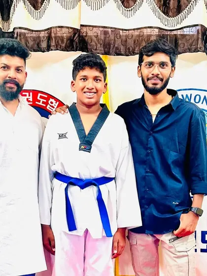 A student and his coaches after a successful belt promotion.