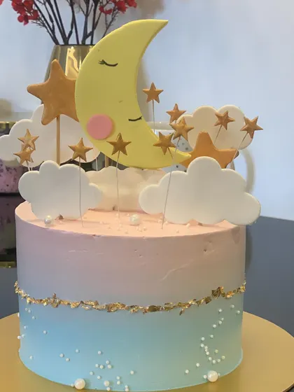 A sweet "Twinkle Twinkle Little Star" baby shower cake. The pink and blue ombre design is topped with a sleeping moon and fondant stars.