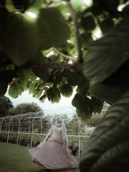 A whimsical shot of a bride twirling in a garden, framed by leaves that create a natural, dreamy effect.