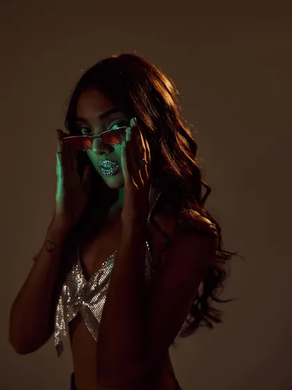 A moody, high-fashion shot with a "hot and unbothered" vibe. I styled a silver chainmail top with crystal-studded lips and colored sunglasses, using low-key lighting to create a glamorous and edgy feel.