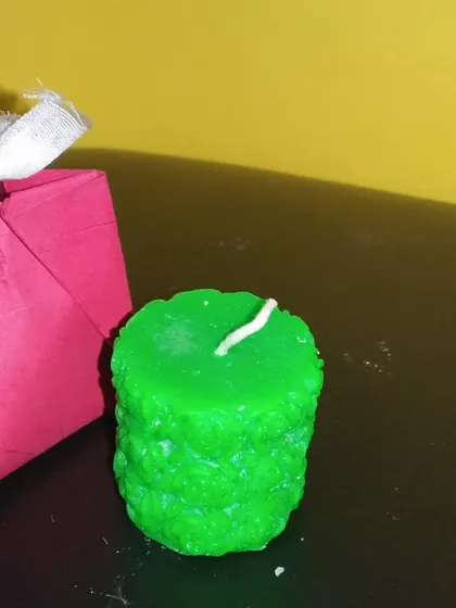 A textured green candle shown next to a small, handmade gift bag. This shows how my decorative candles can be packaged to make a thoughtful and unique present.