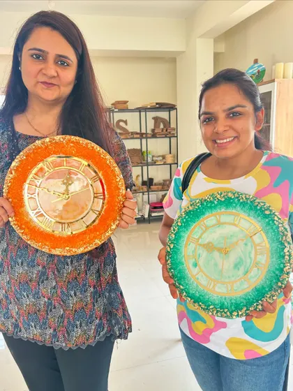 Two guests showing off their vibrant geode-style epoxy resin clocks. You can choose your own colors and crystals to create a truly unique timepiece.