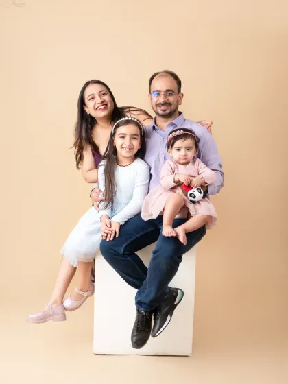 A beautiful family portrait with two daughters, showcasing coordinated outfits and happy smiles.