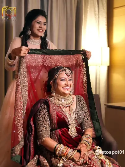 A playful and happy moment as the bride's sister helps her with her veil. The genuine smiles and laughter show the strong bond and joy of the occasion.