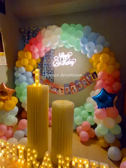 A colorful first birthday setup with a pastel rainbow balloon ring. I also included a Mickey Mouse themed banner, a light-up number '1', and the child's name in marquee letters.