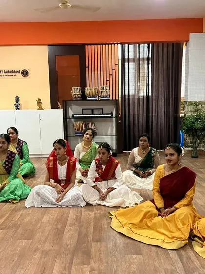 Kathak students in elegant costumes seated gracefully as they await their practical examination.