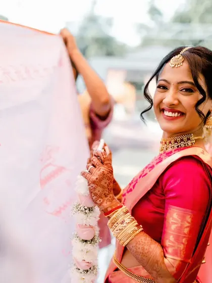 A candid moment during the wedding rituals. The bride's makeup is fresh and radiant, and her hair is beautifully adorned with flowers.