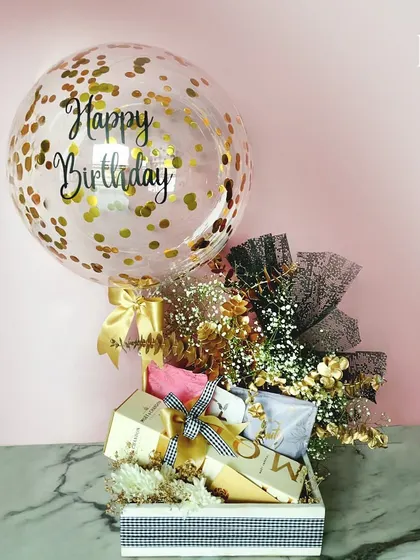 A birthday hamper that sparkles with celebration. Featuring a gold confetti balloon, a bottle of Moët & Chandon champagne, and other gourmet treats, this black, white, and gold themed gift is perfect for a glamorous and festive birthday.
