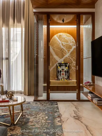 The sun-kissed living room seamlessly incorporates the pooja room into its decor. This integration creates a harmonious flow, setting a warm and spiritual tone for the entire open-plan space.