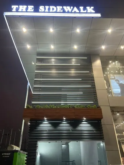 A close-up of the facade detailing, showing the interplay of horizontal louvers, integrated LED lighting, and the main building signage.