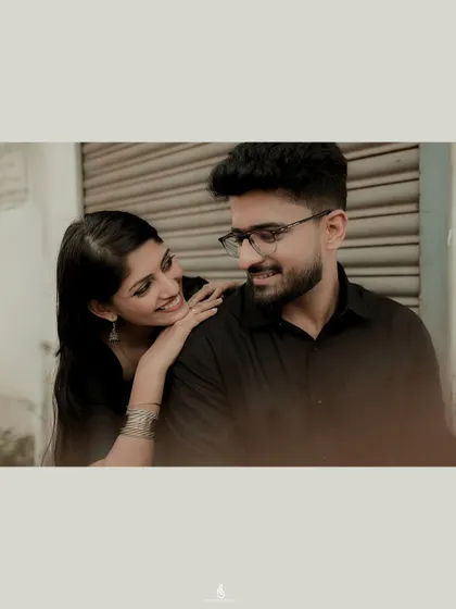A close-up, intimate moment against a simple urban backdrop. The focus is entirely on the couple's connection and emotion.
