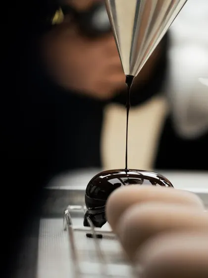 A glossy, perfect mirror glaze being poured over a petit gâteau. Watching a master like Chef Bachour at work is an invaluable learning experience.