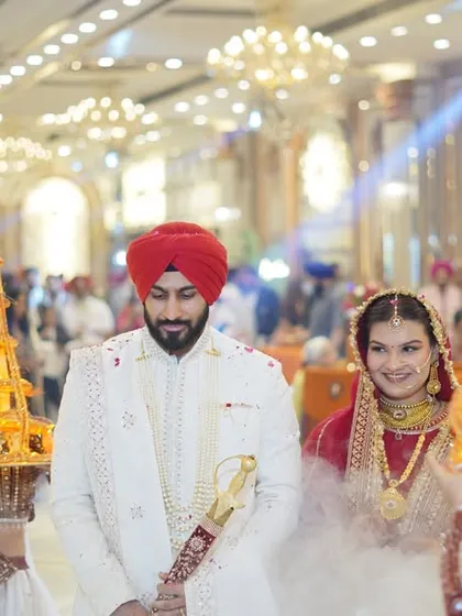 A royal entrance for the couple, flanked by attendants carrying decorative lights. This wide shot captures the grandeur of the moment.