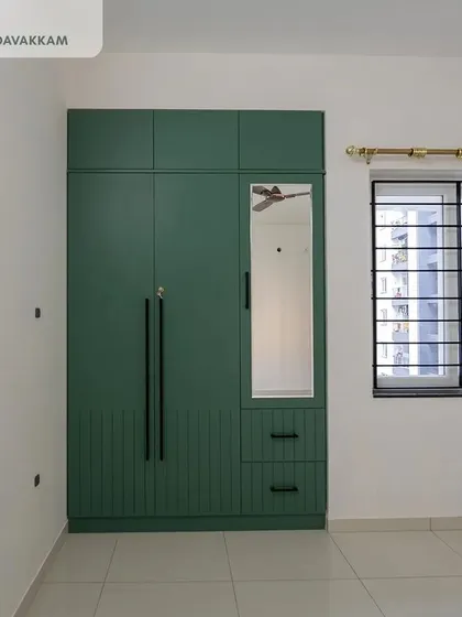 The guest bedroom wardrobe at Casagrand Zenith, designed with English Ivy laminates, long black handles, and an integrated mirror on the shutter to save space.