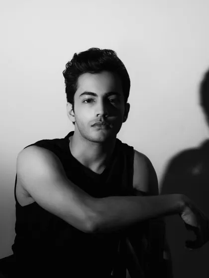 A confident and direct black and white headshot. The simple background and strong eye contact make this a very effective shot for casting.