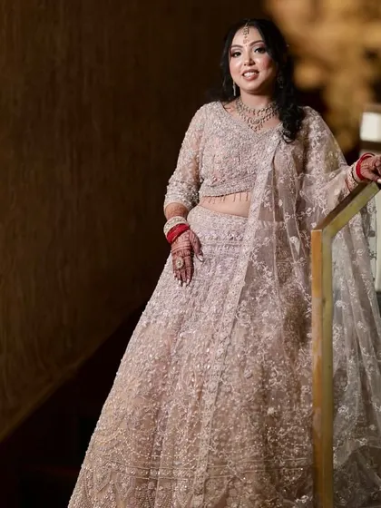 A stunning full-length shot of the bride on a staircase, her beige lehenga and soft makeup creating a look of pure elegance.
