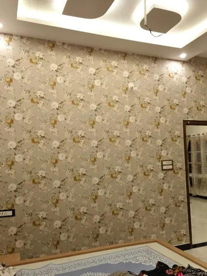This delicate floral wallpaper with a neutral color palette brings a soft, romantic feel to a bedroom. It covers the entire wall, creating a cohesive and serene backdrop that complements the room's lighting and decor.