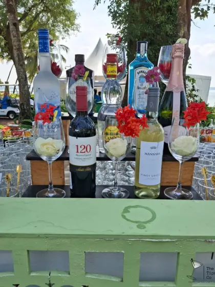 A beautiful outdoor bar setup featuring a selection of premium wines and spirits. The floral arrangements and elegant glassware create a sophisticated atmosphere perfect for a brunch or daytime event.