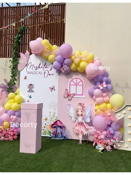 Welcome to Mishita's "Magical One" fairy-themed party. This beautiful backdrop features a fairy house, pastel balloons, floral details, and a light-up number one.