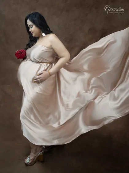 An artistic shot that uses the flowing fabric to create a sense of movement and grace. The side profile beautifully highlights her baby bump.