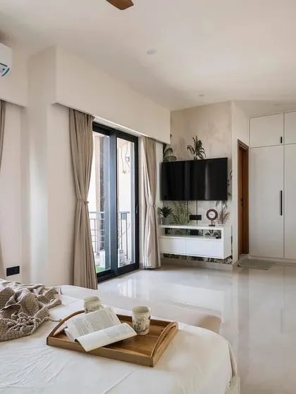 This master bedroom in the penthouse is designed to be spacious and light-filled. The minimal furniture, white walls, and large windows create an airy, open feel, making it a serene retreat from the city.