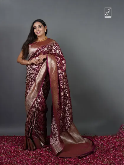 A full-length portrait against a simple grey backdrop, ensuring the traditional saree and the model's elegance are the sole focus.