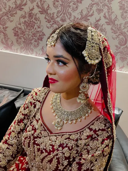 A side profile of the bride, highlighting the flawless makeup and the intricate details of her traditional jewelry.
