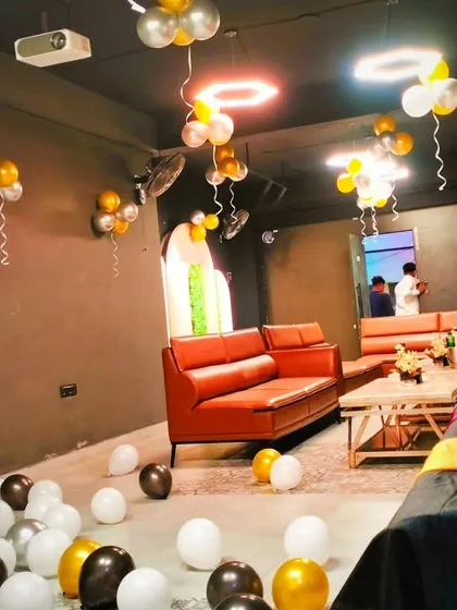 Another view of a party setup in a private room, with gold, black, and white balloons scattered on the floor and hung from the ceiling.