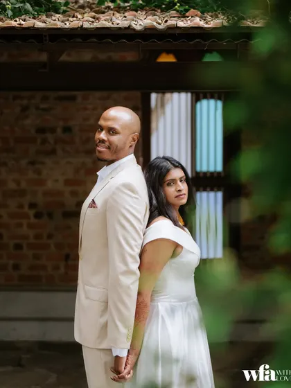 A modern pose against a classic backdrop. The couple stands back-to-back, creating a stylish portrait against the brick walls and stained-glass windows.