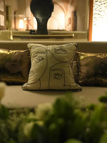 A close-up of a modern, line-art pillow on a sofa. We use stylish soft furnishings to enhance the theme and comfort of our lounge areas.