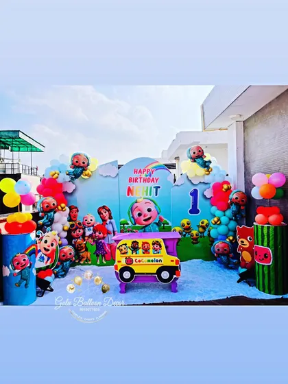 A complete outdoor setup for a Cocomelon-themed first birthday, with all the characters, a custom backdrop, and a colorful balloon arrangement.