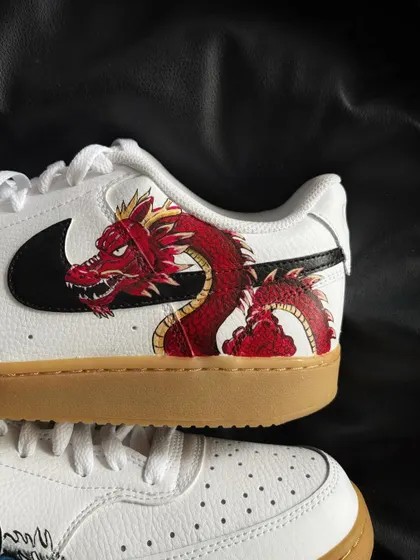 A close-up of a custom Nike Court Vision sneaker with a fierce red dragon design.