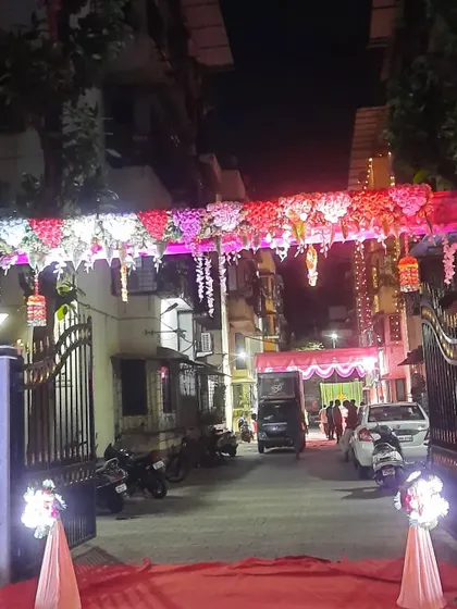 A beautiful floral entrance gate for a Haldi event at night. The lighting makes the flowers and drapes stand out.