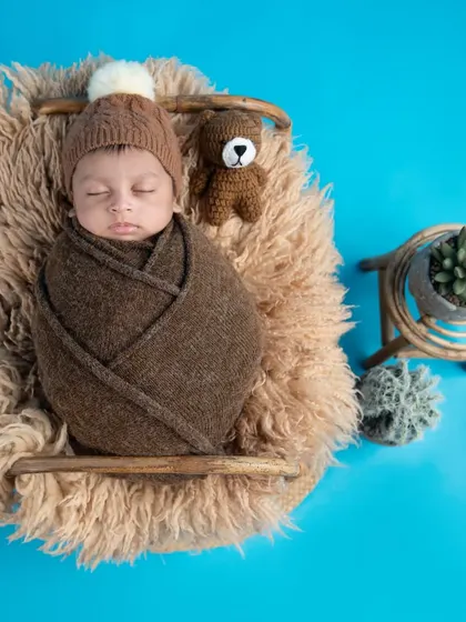 This little one is resting comfortably in a fuzzy basket against a bright blue background. The contrast makes the earthy tones of the props pop.