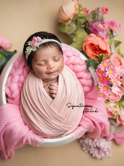 Wrapped in love and surrounded by pink peonies. This classic potato sack pose is a favorite for showcasing how tiny and curled up newborns are, creating a beautiful, artistic portrait.