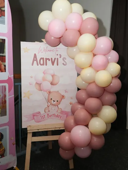 This welcome board for a teddy bear themed first birthday is perfectly placed next to a milestone photo display, creating a lovely corner to celebrate the baby's journey.