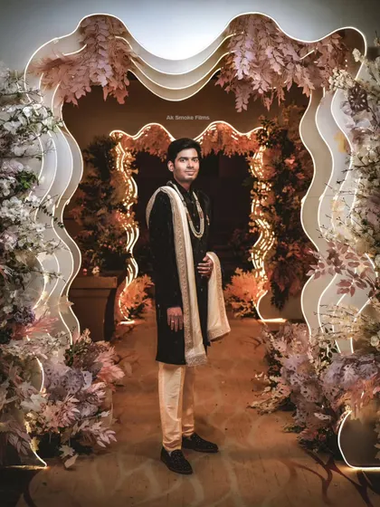A stylish portrait of the groom standing within the unique, wavy floral entrance decor.