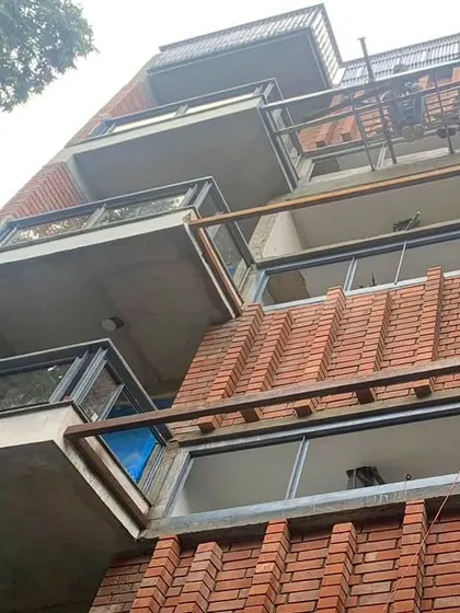 A low-angle view of the house in Panchsheel, emphasizing the texture and rhythm of the custom brickwork. This facade is a clear expression of material honesty, where brick, concrete, and steel are used to define the building's character.