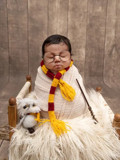 Our little Harry Potter is dreaming of casting spells. This version of the theme places the swaddled newborn in a miniature bed, ready for a magical slumber.
