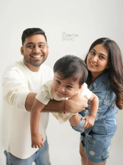 A fun family photo where the parents hold their son, who is making a funny face for the camera. It captures their playful dynamic perfectly.