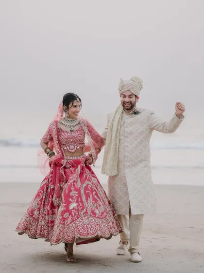 A candid shot of the couple walking and laughing on the beach after their ceremony, capturing a moment of pure, uninhibited joy.