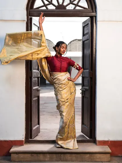 The same cream saree and maroon blouse, captured in a dynamic pose to show the beautiful drape and flow of the fabric.