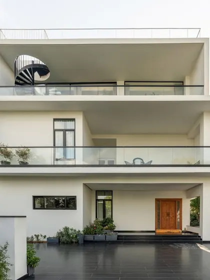 A full view of the simplified house design. The deep, recessed balconies provide privacy and shade, while the clean white volumes create a sense of lightness and order.