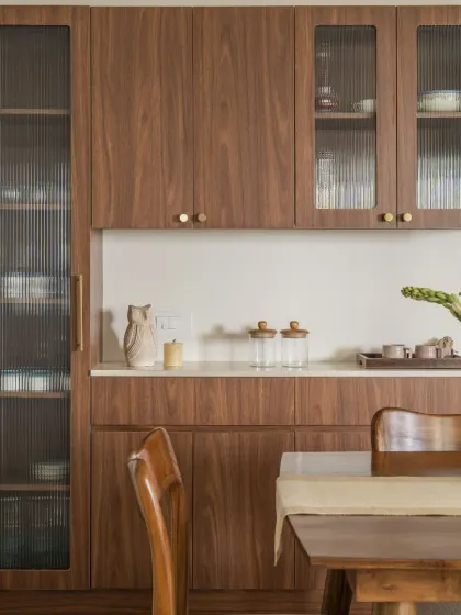 A closer look at the craftsmanship of the wooden crockery unit, showing the rich grain of the wood and the texture of the fluted glass.
